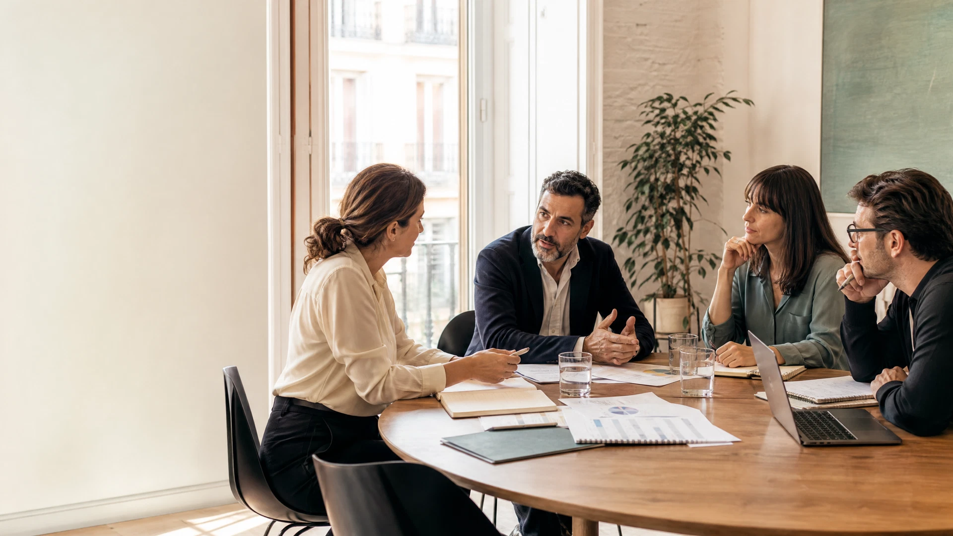 Profesionales conversando alrededor de una mesa de trabajo